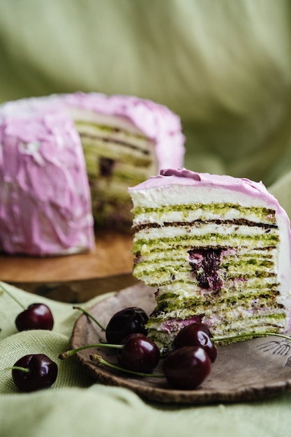 Bolo multicamadas de pistache com cereja em uma superfície verde