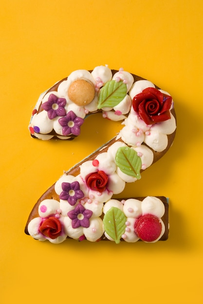 Foto bolo número dois, decorado com flores e macarons isolados