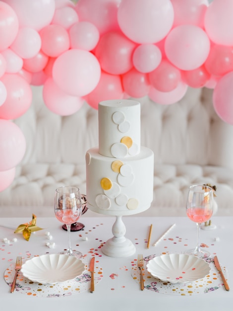 Bolo para festa natalícia. de mesa em cores brilhantes para crianças, pratos de papel elegantes, copos de talheres de ouro. conceito de aniversário de menina. decoração de balões rosa