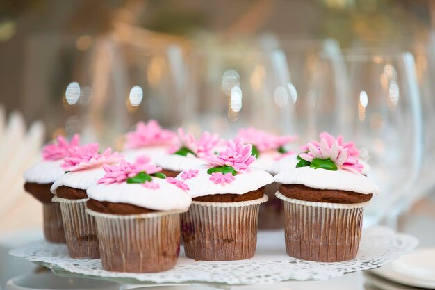 Bolo para uma mesa de buffet Um grupo de pequenos cupcakes decorados com flores creme rosa