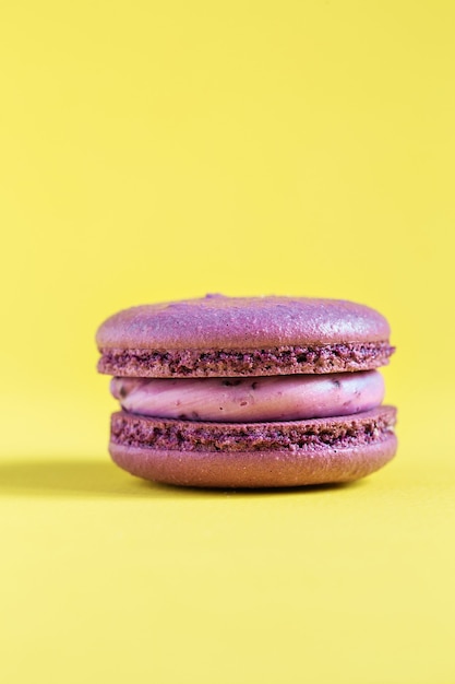 bolo roxo macaron ou macaroon na parede amarela. biscoitos de amêndoa coloridos. macaroon francês