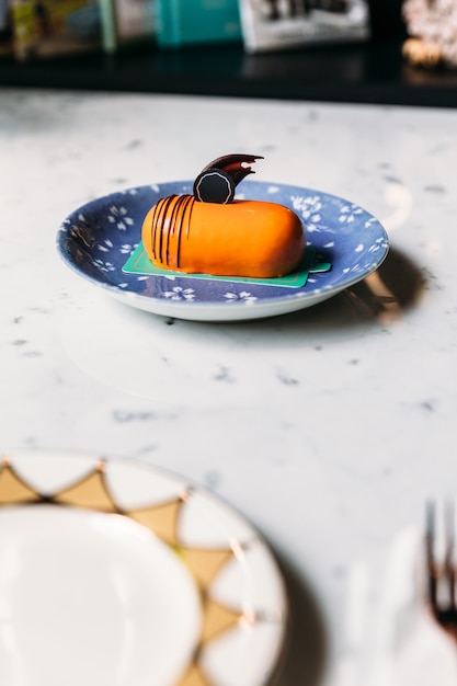 Bolo tailandês clássico das musses do chá decorado com chocolate na placa azul na tabela superior de mármore.