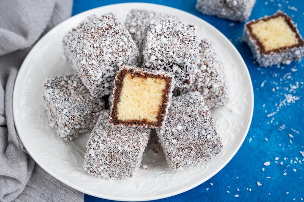 Bolo tradicional australiano lamington em esmalte de chocolate e flocos de coco em um prato branco