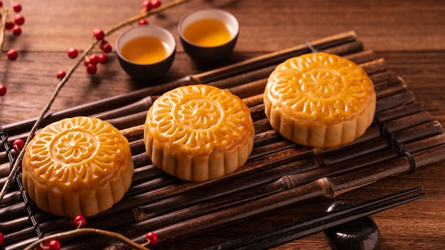 Bolo tradicional chinês Mooncake Mooncake com xícaras de chá em uma bandeja de advertência de bambu sobre fundo de madeira para o Festival do Meio Outono, close-up