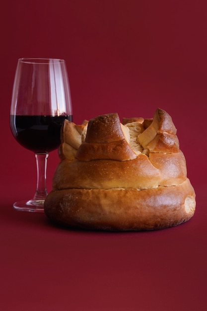 Foto bolo tradicional português fogaca com um copo de vinho do porto em fundo vermelho filmado em estúdio