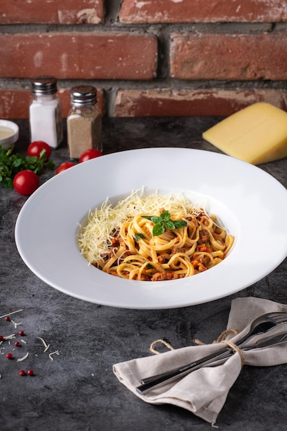 Boloñesa de pasta italiana en un plato blanco con ingredientes en un menú de restaurante de fondo oscuro