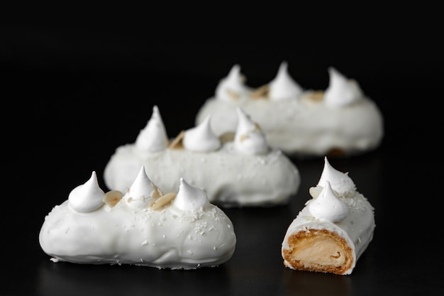 Bolos apetitosos deliciosos com creme de chocolate branco e coco em um fundo preto