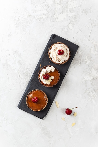 Bolos caseiros crus com creme de coco, cerejas e amêndoas