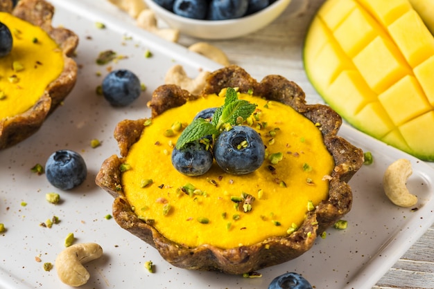 Bolos caseiros de manga crua com frutas frescas, pistache e hortelã. conceito de comida sem glúten vegan saudável