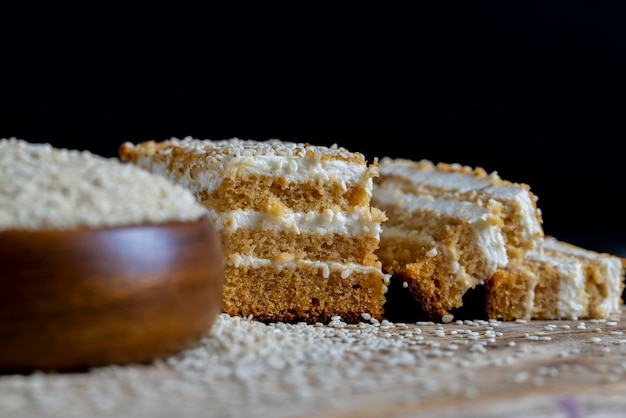 Bolos cremosos de creme e caramelo polvilhados com sementes de gergelim durante a preparação da sobremesa bolo em camadas com sementes de gergelim