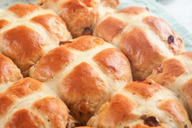 Bolos cruzados calientes de Pascua Trataciones tradicionales de Pascua Bolos cruzados con pasas, mantequilla de chocolate, huevos de caramelo con flores de cereza o manzana en fondos de madera rústica y ligera Comida de Pascua