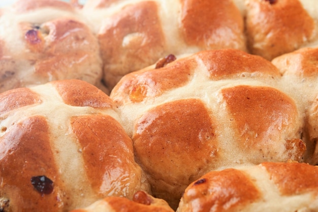 Bolos cruzados calientes de Pascua Trataciones tradicionales de Pascua Bolos cruzados con pasas, mantequilla de chocolate, huevos de caramelo con flores de cereza o manzana en fondos de madera rústica y ligera Comida de Pascua