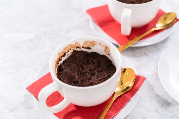 Bolos de caneca de chocolate recém-assados em copos brancos.