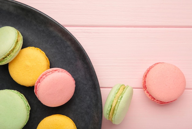 Bolos de macarons coloridos em fundo rosa Pequenos bolos franceses no prato Espaço para texto