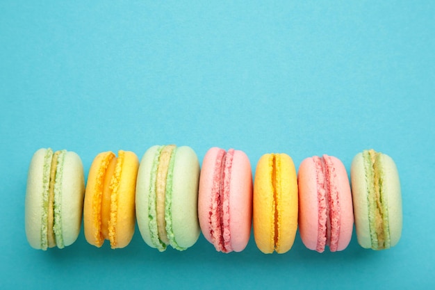 Bolos de macarons coloridos sobre fundo azul Pequenos bolos franceses