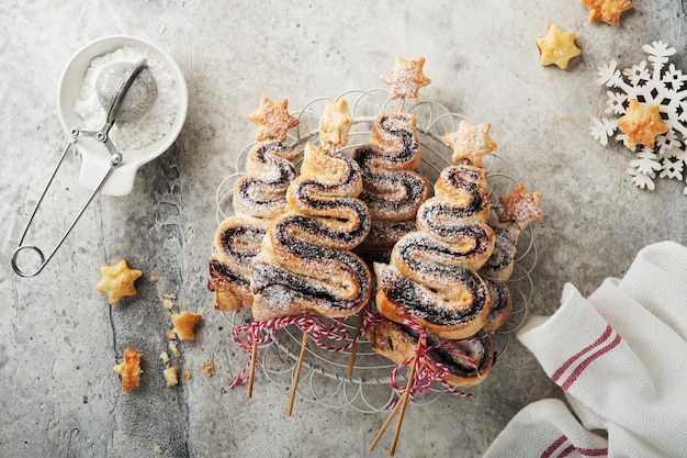 Bolos de massa folhada em forma de árvore de Natal com recheio de chocolate, açúcar em pó e pirulitos no velho fundo branco de madeira Natal Ano Novo Aperitivo Ideia festiva para o jantar de Natal ou Ano Novo