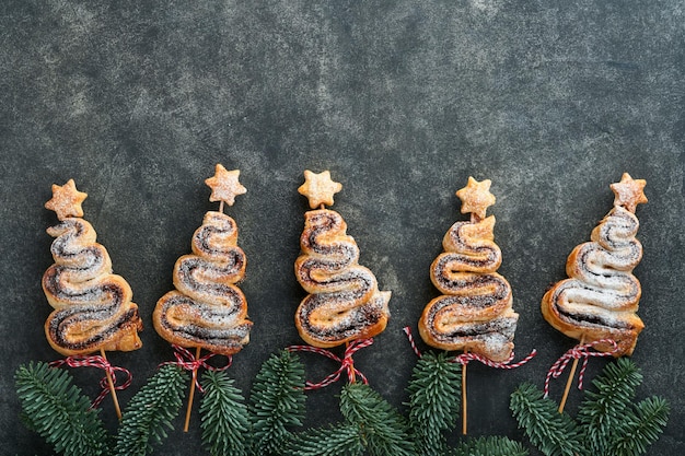 Bolos de massa folhada em forma de árvore de Natal com recheio de chocolate em pó e pirulitos no velho fundo escuro Aperitivo de Ano Novo de Natal Ideia festiva para o jantar de Natal ou Ano Novo