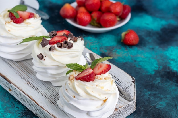 Bolos de merengue Pavlova com chantilly e morangos frescos folhas de hortelã Foco seletivo