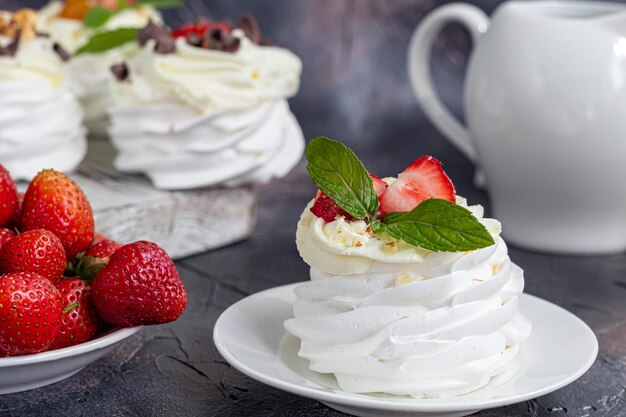 Bolos de merengue Pavlova com chantilly e morangos frescos folhas de hortelã Foco seletivo