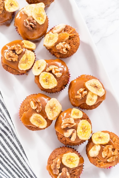 Bolos de pão de banana recém-assados regados com caramelo caseiro, decorados com nozes e chips de banana.