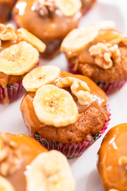 Bolos de pão de banana recém-assados regados com caramelo caseiro, decorados com nozes e chips de banana.