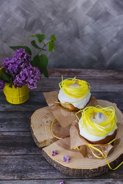 Bolos de Páscoa decorados com ninho amarelo e ovos lilás sobre fundo Pão de Páscoa Tradicional Kulich Paska