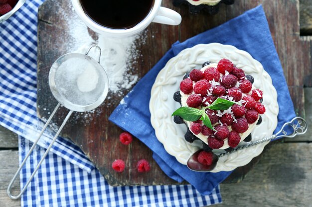 Bolos doces com framboesas na mesa de madeira