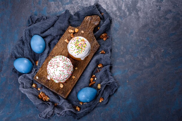 Bolos festivos com esmalte branco, nozes e passas com ovos de Páscoa na mesa festiva. Preparativos para a Páscoa