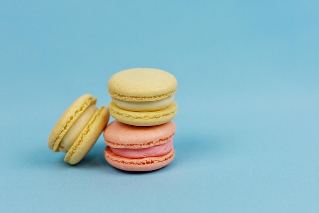 Bolos multicoloridos sobre fundo azul com espaço para copiar Doces de macaroons de laranja