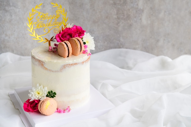 Bolos nus bonitos decorados com Macaron e flor rosa em fundo de pano branco. conceito moderno de bolo e padaria