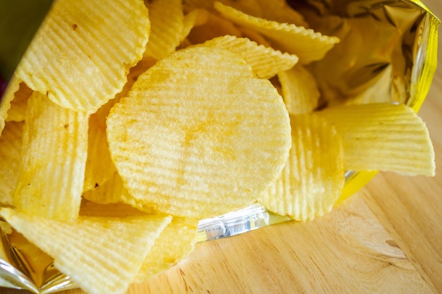 Bolsa abierta de patatas fritas en mesa de madera