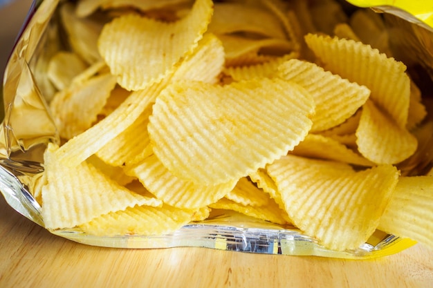 Bolsa abierta de patatas fritas en mesa de madera