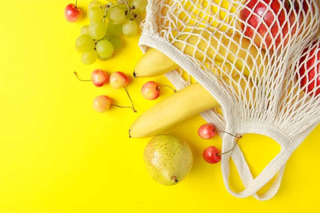 Bolsa de algodón ecológica Frutas maduras en bolsa de malla sobre fondo amarillo Comida vegana orgánica