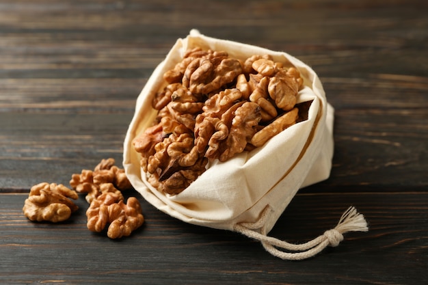 Bolsa de algodón con sabrosas nueces en la pared de madera