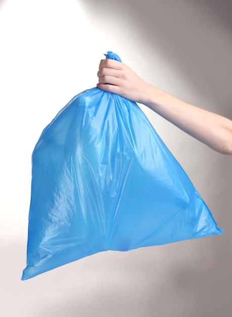 Bolsa de basura azul con basura en la mano aislada en blanco
