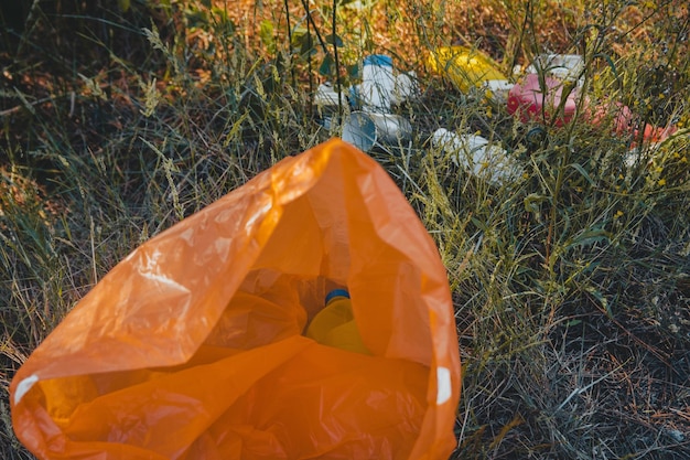 Bolsa de basura de plástico naranja en el suelo - concepto de contaminación ambiental