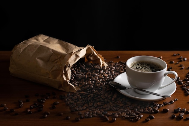 Una bolsa de café de papel marrón se encuentra en una mesa junto a una taza de café.