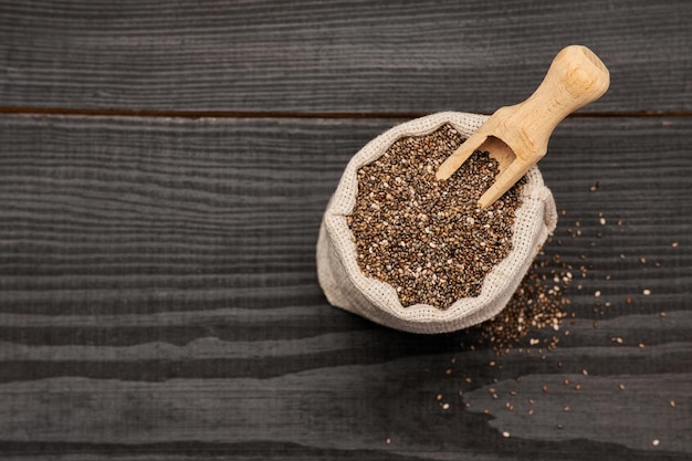 bolsa cheia de sementes de chia naturais orgânicas em fundo escuro de madeira ou mesa