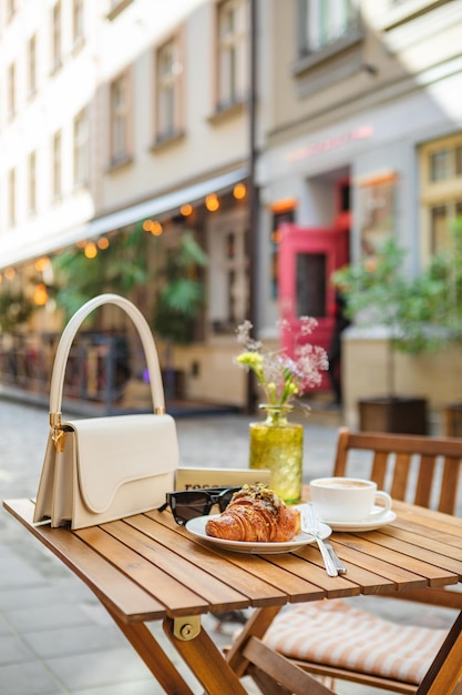 Bolsa com óculos croissant com café na mesa