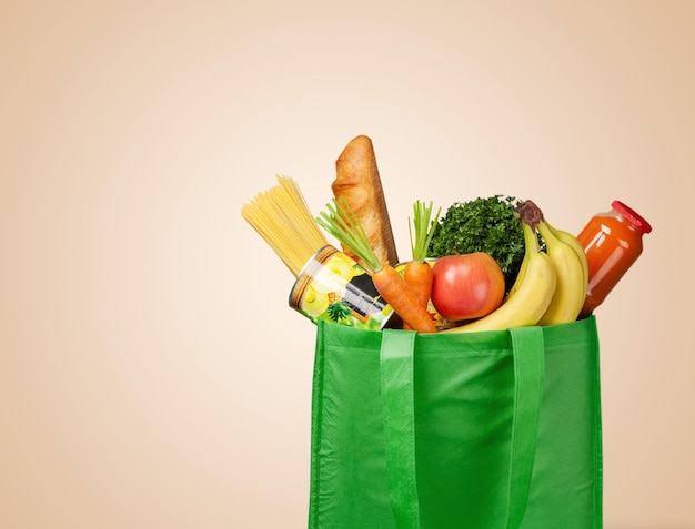 Bolsa de compras completa con vegetales frescos en el fondo