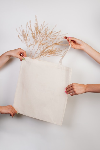 Bolsa de compras ecológica hecha a mano de algodón de maqueta en mano bolsa blanca hecha de materiales reciclados sobre aislante blanco ...