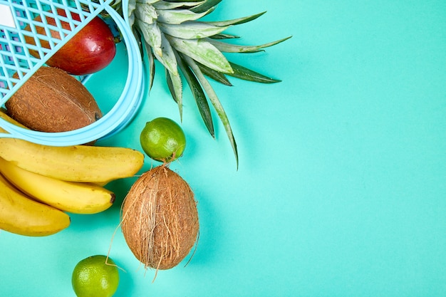 Bolsa de compras con frutas exóticas orgánicas sobre fondo azul.