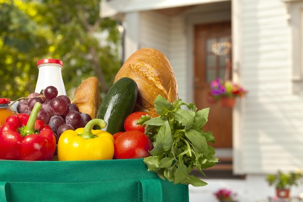 Bolsa de compras con productos y alimentos en la puerta principal.