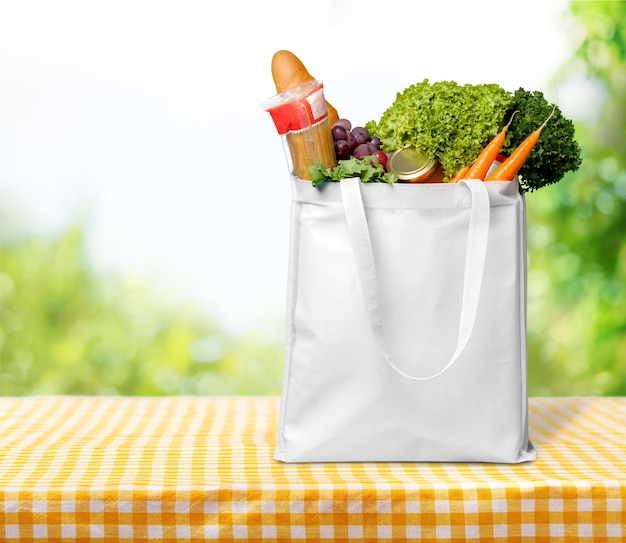 Bolsa de compras con productos comestibles en mesa de madera