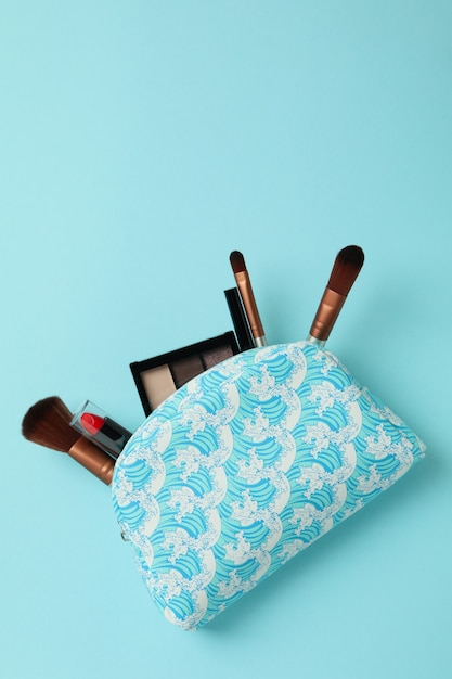 Bolsa de cosméticos con cosméticos sobre fondo azul.