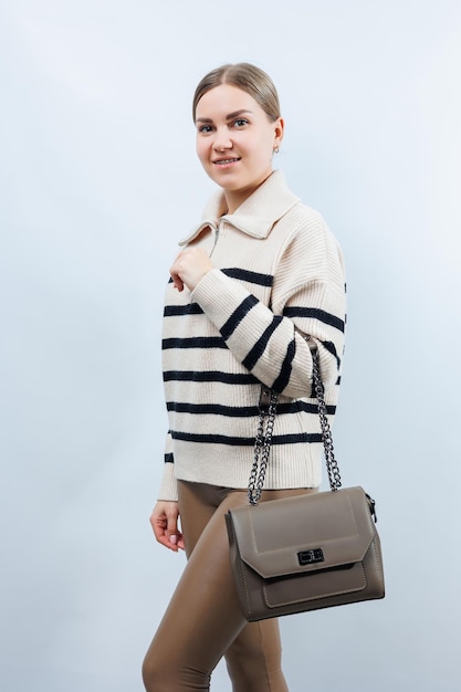 Bolsa de couro bege pequena em uma mão feminina em um fundo branco bolsa de ombro mulher com uma bolsa bege estilo moda vintage e elegância