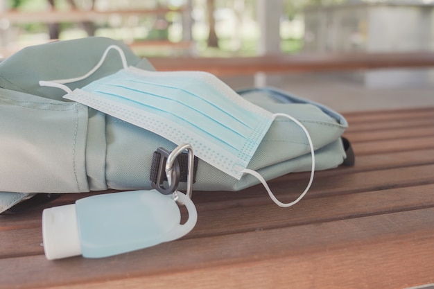 Bolsa de estudante com máscara médica e clipe de desinfetante para as mãos, reabertura da escola