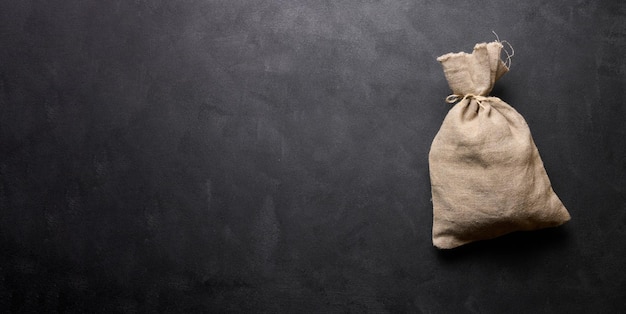 Foto bolsa de lona cheia em um espaço de fundo preto para uma inscrição