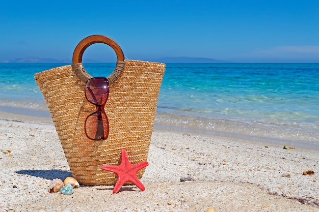 Bolsa de palha e óculos de sol à beira-mar