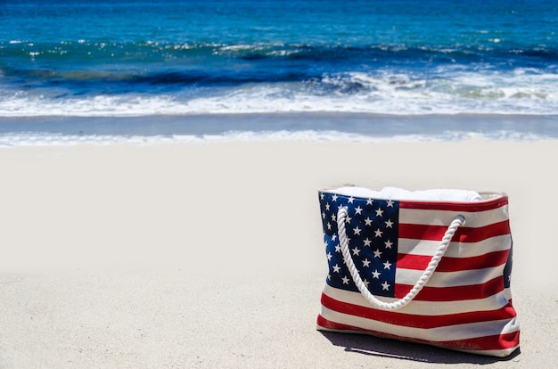 Foto bolsa de praia com cores da bandeira americana perto do oceano